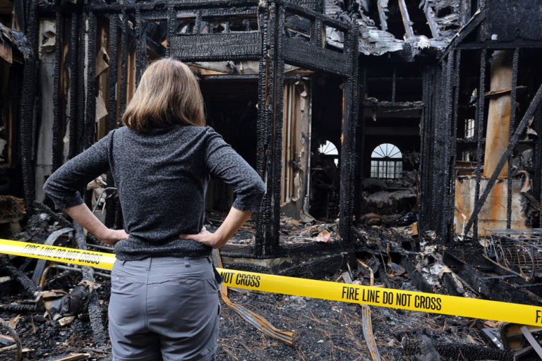 lady standing in front of a burnt structure
