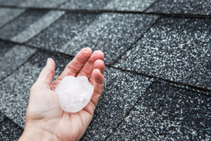 golf ball size hail in a person's hand with roof in background