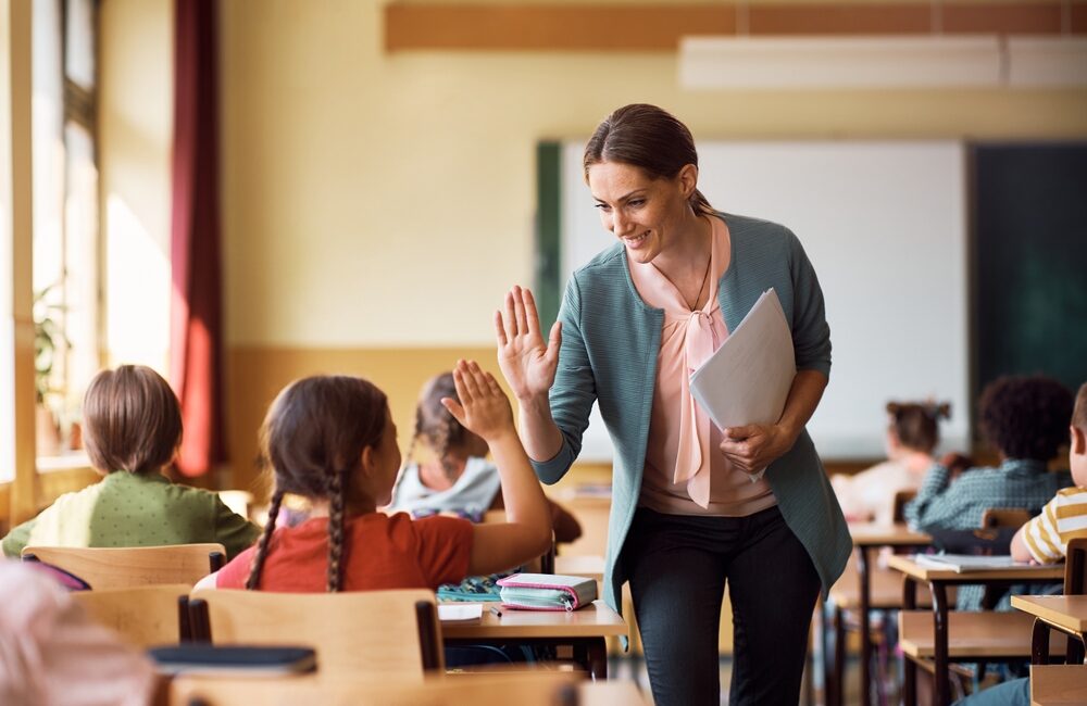 teacher high fiving students in classroom